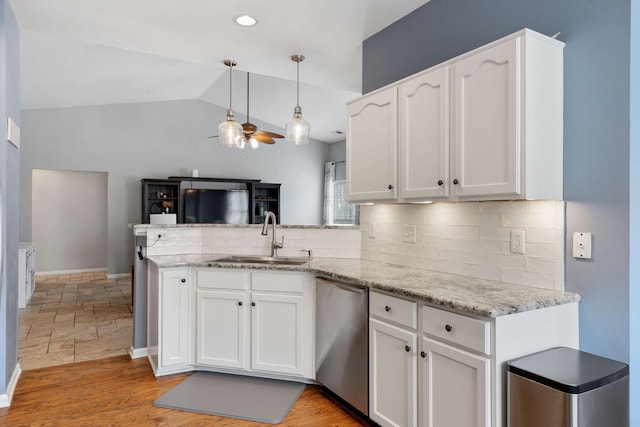 kitchen featuring dishwasher, a peninsula, a sink, and white cabinetry