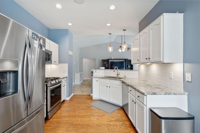 kitchen featuring vaulted ceiling, stainless steel appliances, a sink, and white cabinetry