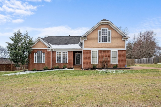 traditional-style home with brick siding, a front lawn, and fence