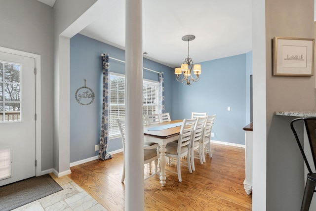 dining room featuring light wood-style flooring, baseboards, and an inviting chandelier