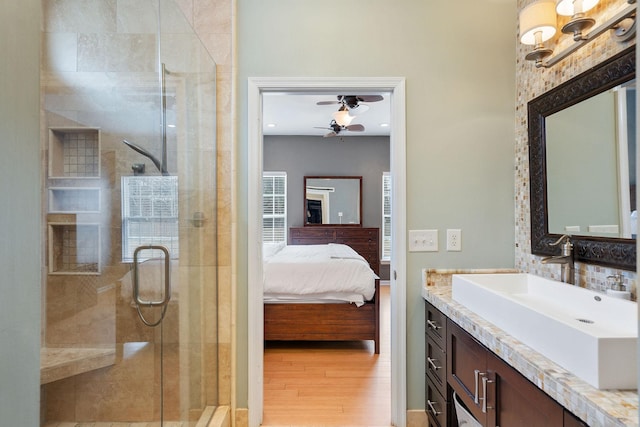 ensuite bathroom with wood finished floors, a stall shower, connected bathroom, and a ceiling fan