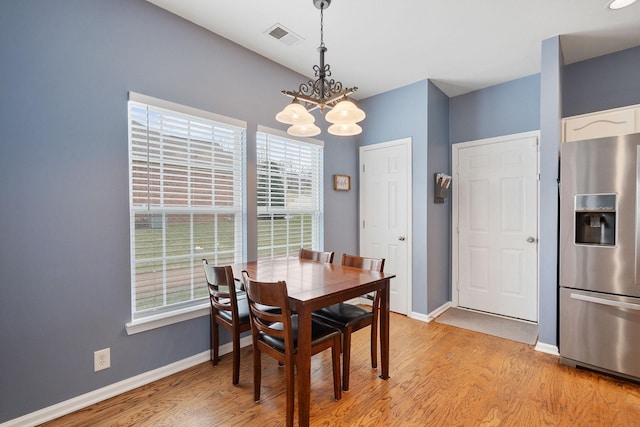 dining area with light wood-style floors, baseboards, visible vents, and a chandelier