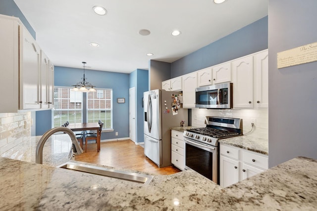 kitchen with stainless steel appliances, backsplash, a sink, and white cabinetry