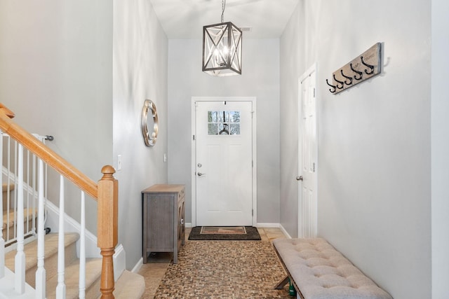 entrance foyer with a chandelier, stairway, and baseboards