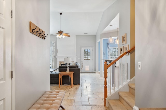 foyer featuring a fireplace, stone tile floors, a high ceiling, baseboards, and stairs