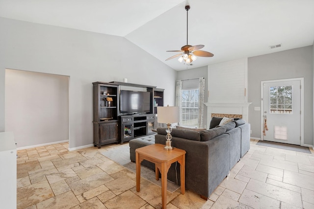 living area featuring lofted ceiling, ceiling fan, stone tile floors, a fireplace, and visible vents