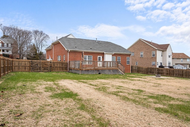 rear view of property featuring brick siding, a yard, and a fenced backyard