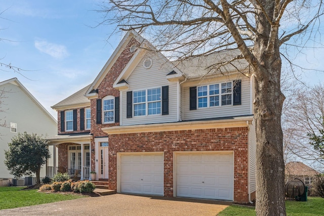 traditional-style house featuring a garage, driveway, brick siding, and cooling unit