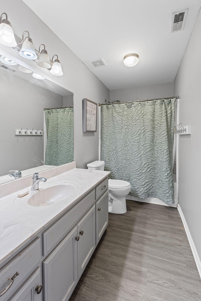 bathroom with toilet, visible vents, wood finished floors, and vanity