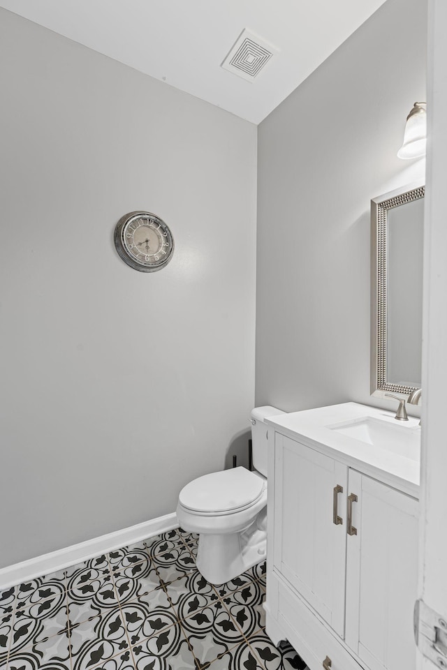 bathroom featuring tile patterned flooring, toilet, vanity, visible vents, and baseboards