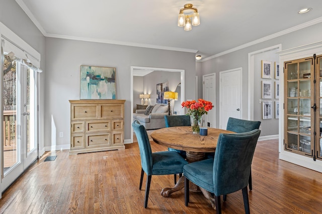 dining space with baseboards, ornamental molding, and light wood-style floors