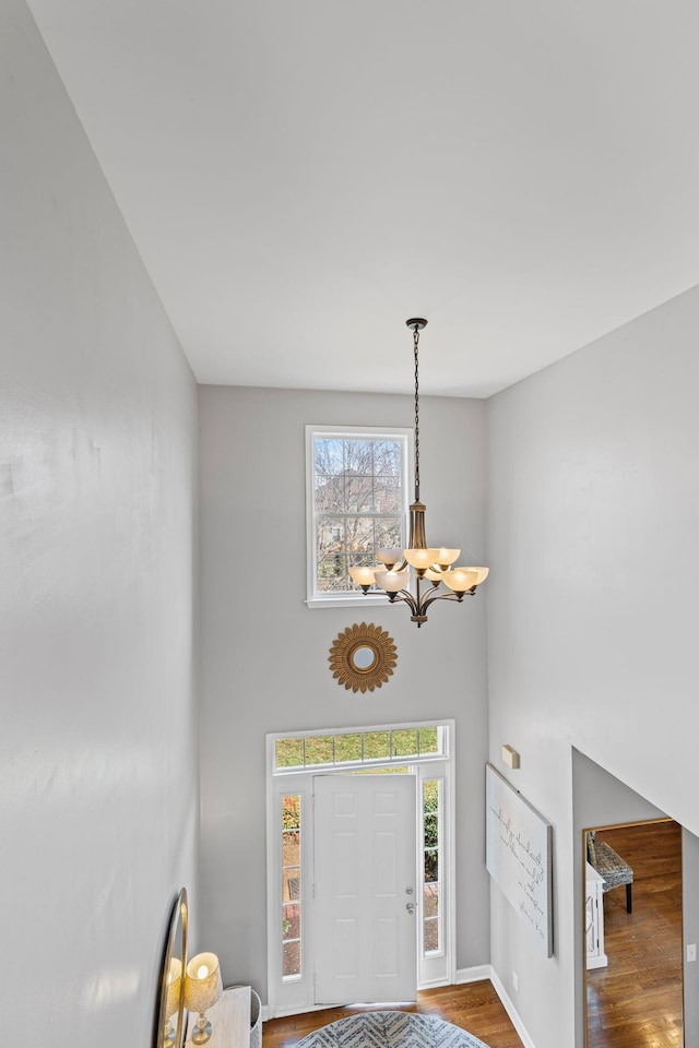 foyer entrance with an inviting chandelier, a high ceiling, and baseboards