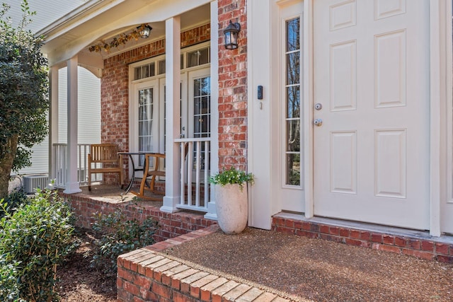 entrance to property with a porch and brick siding