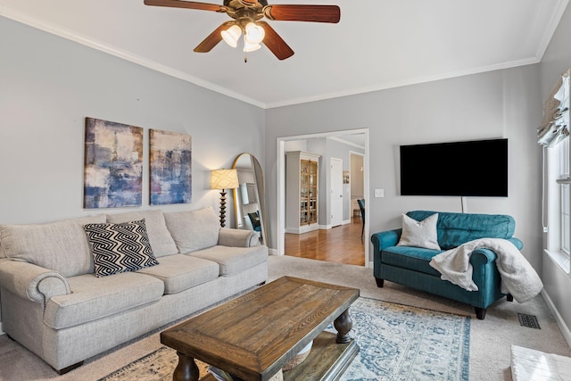 living room featuring baseboards, ceiling fan, visible vents, and crown molding