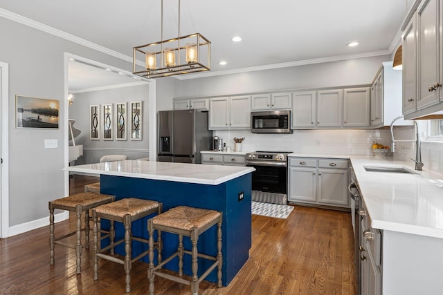 kitchen featuring stainless steel appliances, dark wood-style flooring, a sink, and a kitchen island