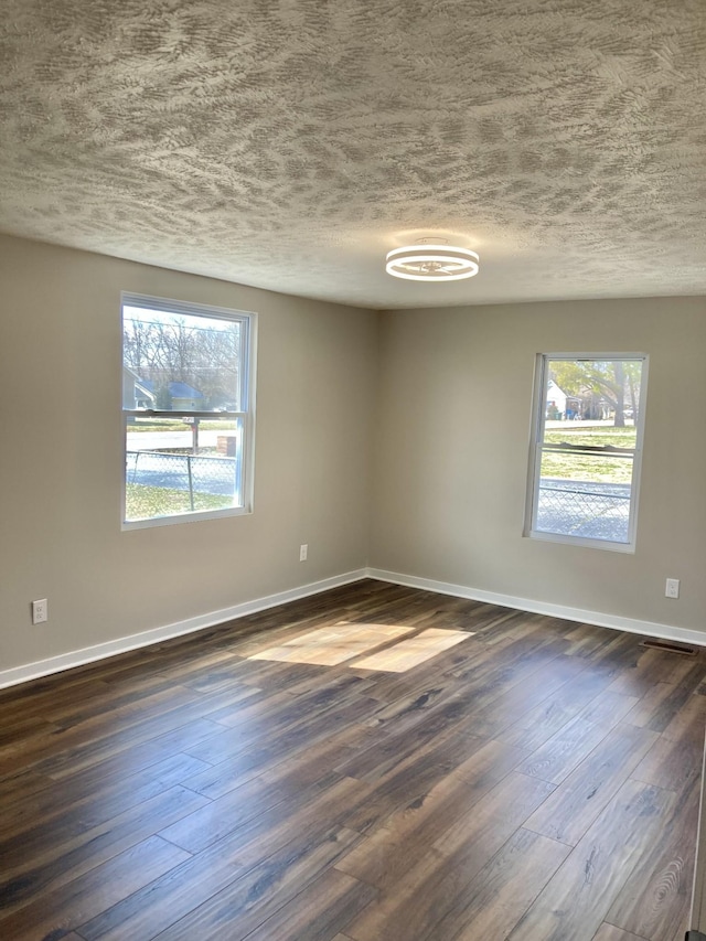 spare room with baseboards, dark wood-style flooring, and a textured ceiling