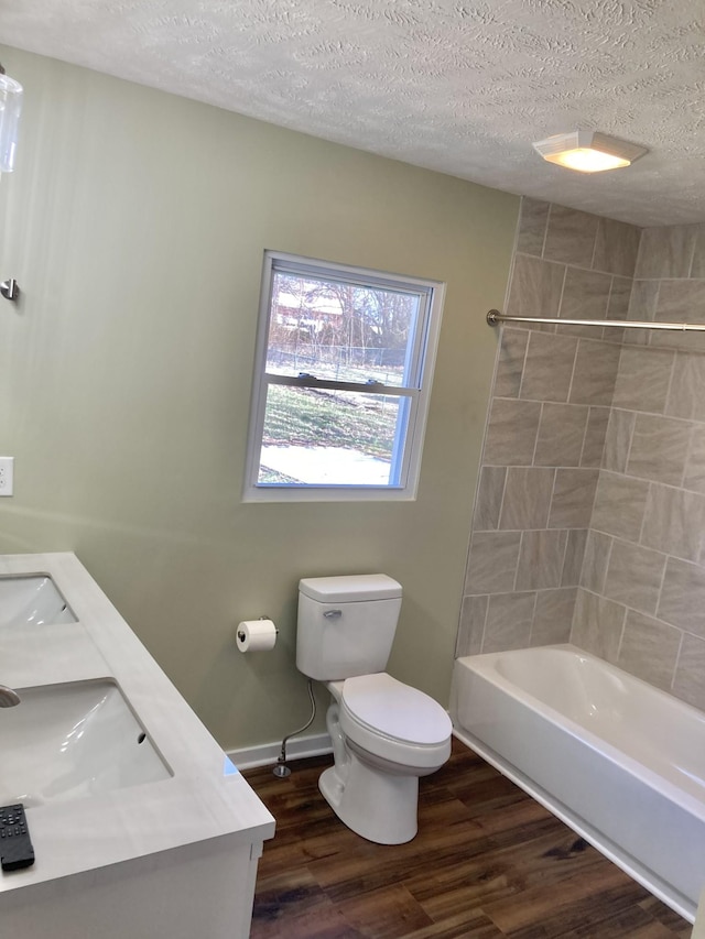 full bath with baseboards, toilet, wood finished floors, a textured ceiling, and a sink