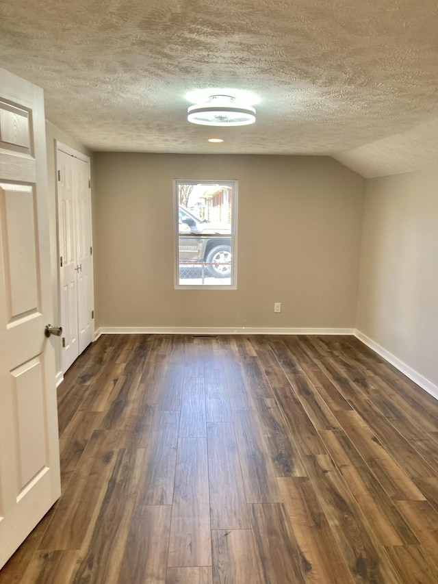 unfurnished room featuring a textured ceiling, baseboards, and dark wood-style flooring