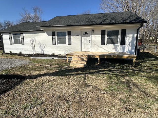 view of front of property featuring a front lawn and roof with shingles