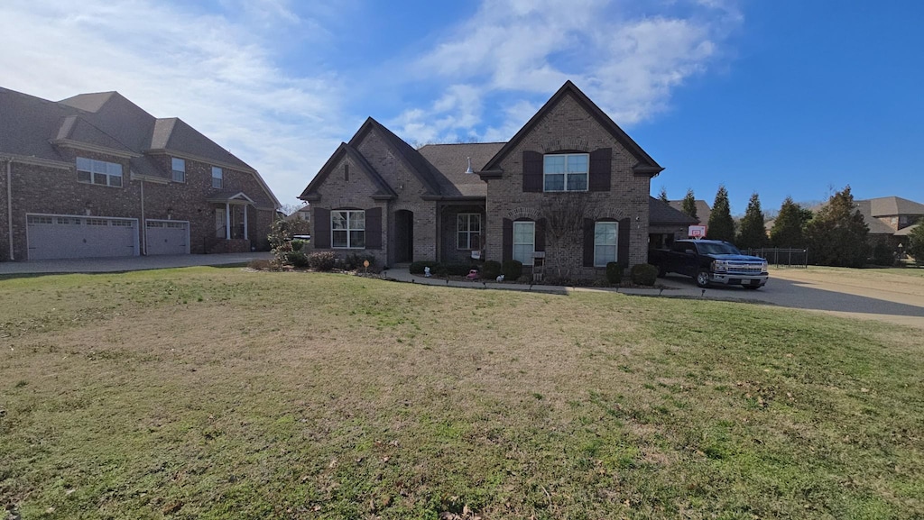 view of front facade featuring an attached garage, a front yard, and brick siding