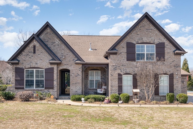 french country style house featuring brick siding and a front lawn