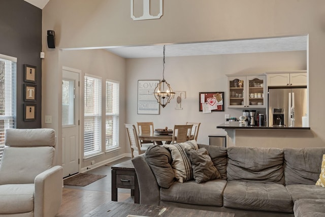 living room with baseboards, an inviting chandelier, and wood finished floors