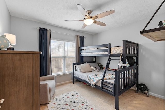 carpeted bedroom featuring ceiling fan, a textured ceiling, and baseboards