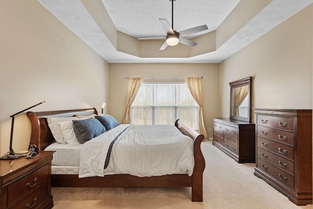 bedroom with light carpet, ceiling fan, a raised ceiling, and a textured ceiling