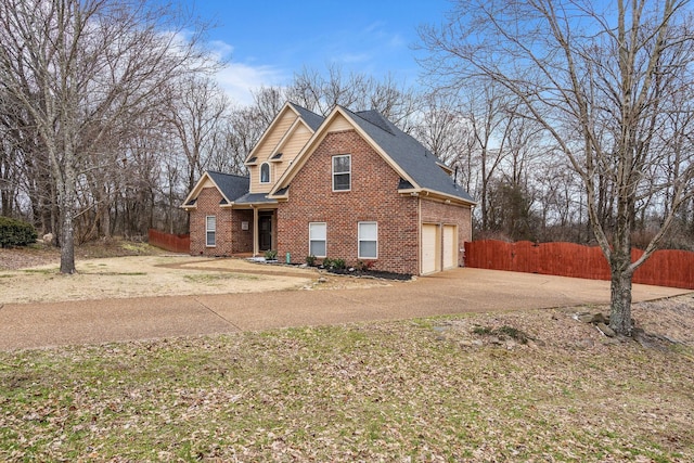 traditional home with concrete driveway, brick siding, an attached garage, and fence