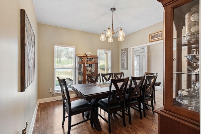 dining area featuring an inviting chandelier, baseboards, and dark wood-style flooring