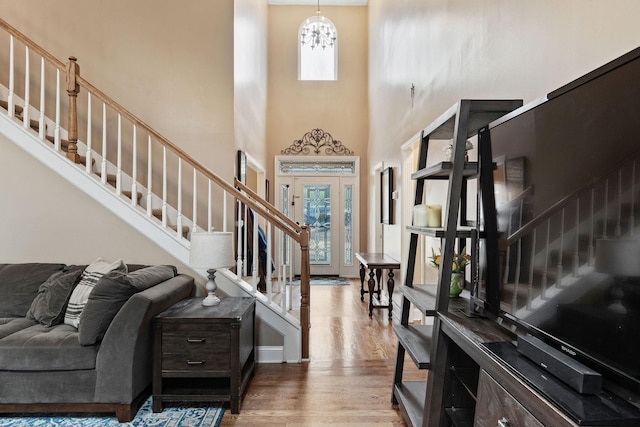 entryway featuring stairs, baseboards, wood finished floors, and a notable chandelier