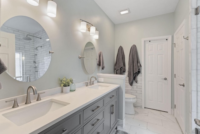 full bath featuring marble finish floor, tiled shower, a sink, and toilet