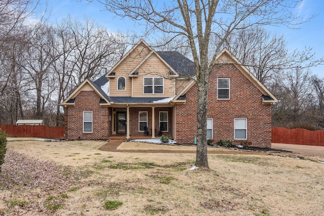 craftsman-style house with brick siding, a front yard, fence, and a shingled roof