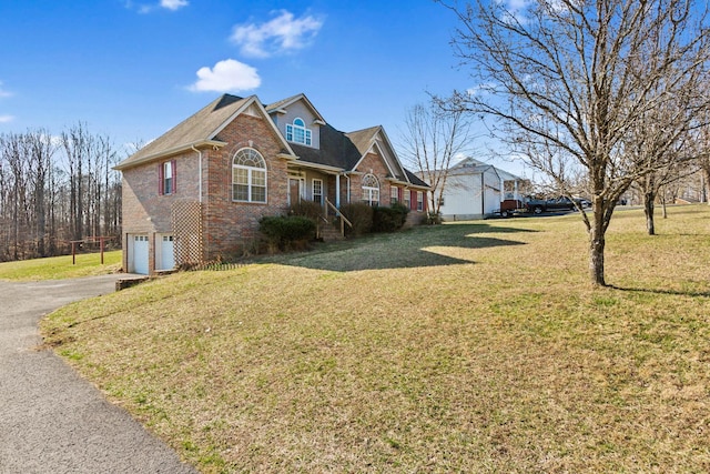 view of front of property with aphalt driveway, brick siding, a garage, and a front lawn