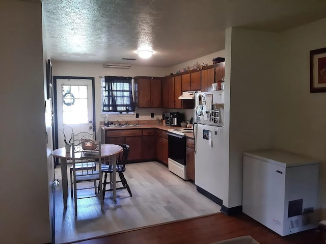 kitchen featuring electric range oven, refrigerator, freestanding refrigerator, under cabinet range hood, and light wood-style floors