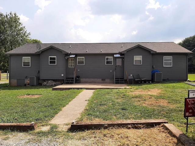 back of property featuring entry steps, a lawn, and central AC unit