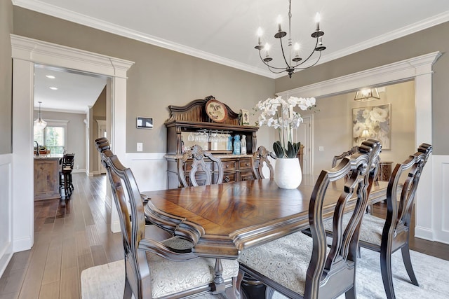 dining room with ornamental molding, a notable chandelier, and wood finished floors