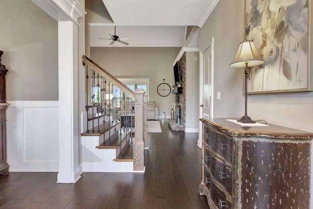 entrance foyer with baseboards, a ceiling fan, a wainscoted wall, dark wood-style flooring, and stairs