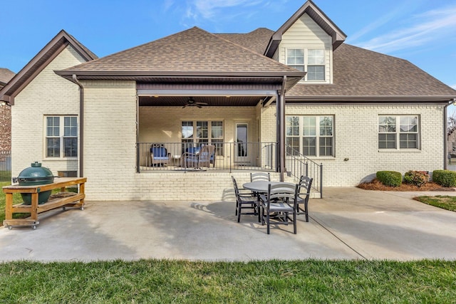 back of house with roof with shingles, ceiling fan, brick siding, and a patio