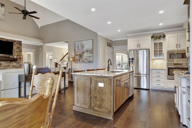 kitchen featuring stainless steel appliances, decorative backsplash, vaulted ceiling, a sink, and light stone countertops