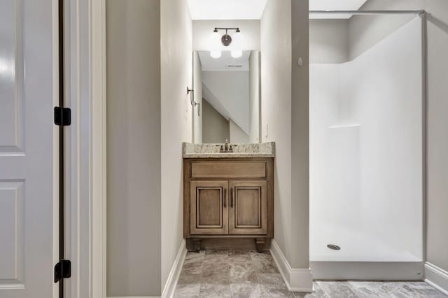 full bath with a stall shower, vanity, and baseboards