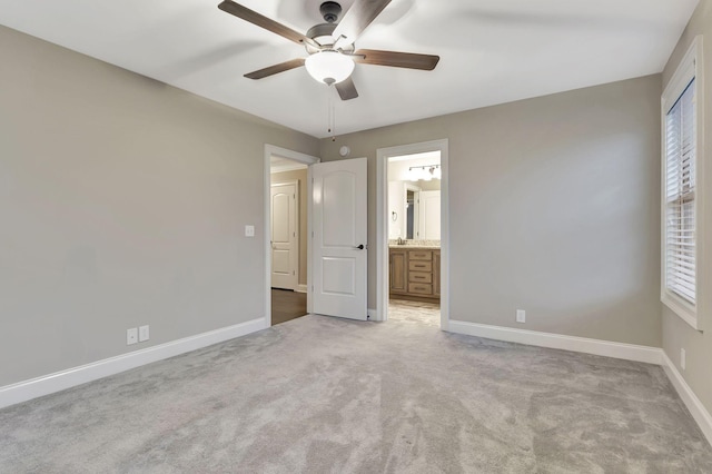 unfurnished bedroom featuring light carpet, ceiling fan, connected bathroom, and baseboards