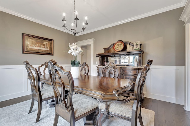 dining space with a chandelier, a wainscoted wall, wood finished floors, and crown molding