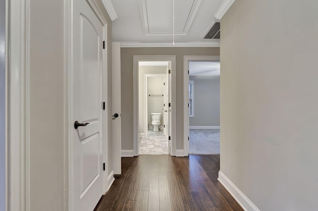 corridor with attic access, baseboards, visible vents, ornamental molding, and dark wood-style flooring