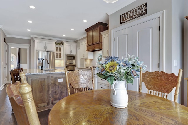 dining area with dark wood finished floors, crown molding, and recessed lighting