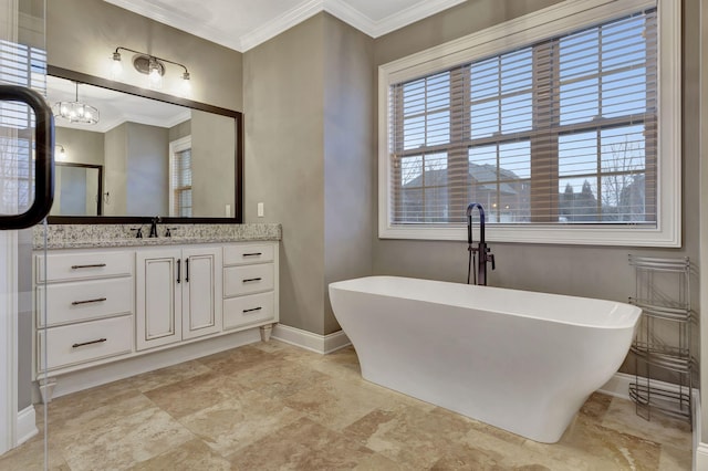 bathroom featuring ornamental molding, a freestanding tub, vanity, and baseboards