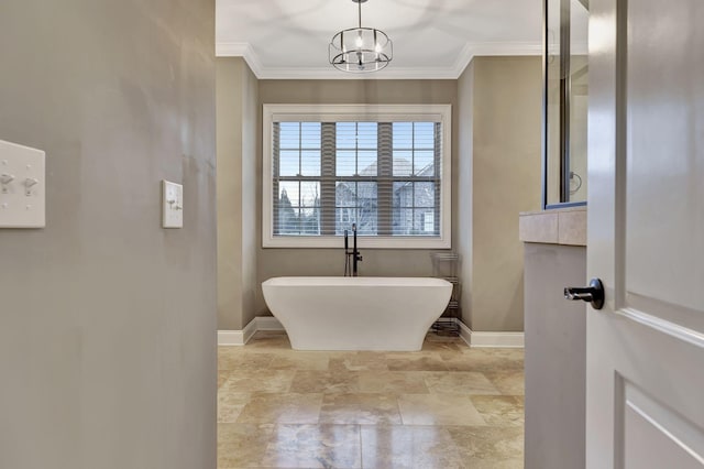 full bath featuring ornamental molding, a chandelier, a freestanding bath, and baseboards