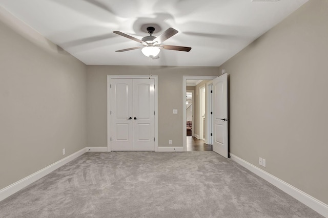 unfurnished bedroom with carpet floors, a closet, a ceiling fan, and baseboards