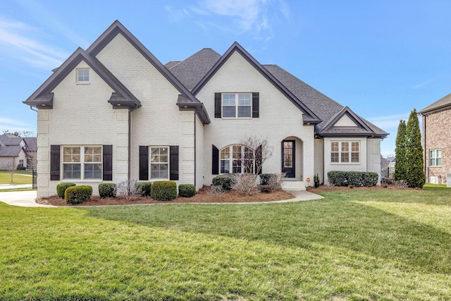 french country inspired facade featuring brick siding and a front yard