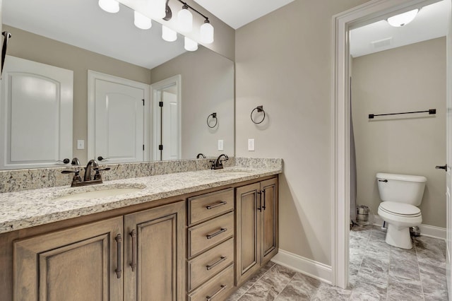 full bath with double vanity, a sink, toilet, and baseboards